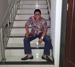 Kepala Dinas Dikpora Kabupaten Dompu H Ichtiar Yusuf, duduk di tangga menuju lantai dua Pengadilan Tipikor Mataram-NTB, Kamis (1/12). (foto istimewa/lakeynews.com)